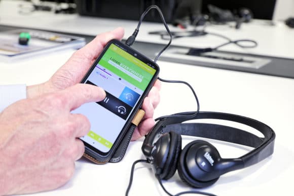 Smartphone mit Listen EVERYWHERE App und angeschlossenen Kopfhörern