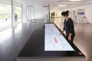 An einem langen Touchscreen-Tisch werden bei Hilti Ideen und Entwicklungsprozesse sichtbar gemacht und Kreativmethoden, systematische Planungsschritte, Einflussfaktoren und Produktentwicklungen thematisiert. Filmeinblendungen ergänzen die Entwicklungslinien.