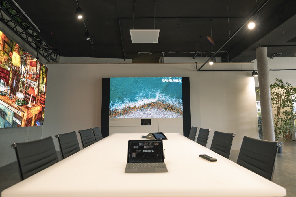 Unilumin Konferenzraumes mit Upanel II 1.2 mm PP-Wall und einer perfekten Integration von Medientechnik, Video-Konferenzlösungen, Mikrofonie, CMS-Software, Mediensteuerung sowie der Konferenzraummöbel