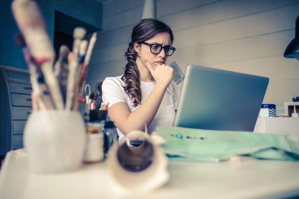 Person mit nachdenklichem Gesichtsausdruck schaut auf Laptop