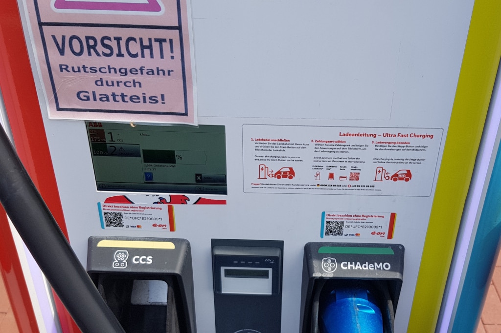 Display, drei kleingedruckte Aufkleber und ein laminierter Gefahrenhinweis an Ladestation