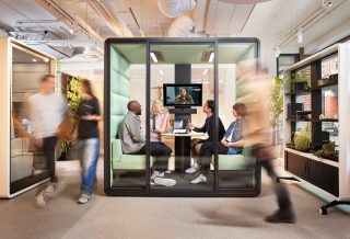 Drei Menschen an Tisch vor Monitor in kleinem Besprechungsraum