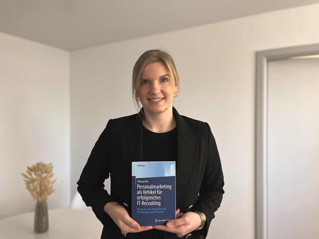 Theresa Fiss hält ihre Masterarbeit in beiden Händen vor dem Körper