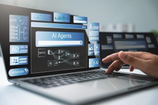 Hand über Tastatur eines Notebooks mit diversen Fenstern und der Aufschrift AI Agents