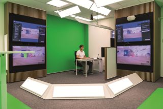 Man an Schreibtisch vor grüner Wand