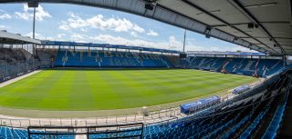 Blick auf den Rasen und die gegenüberliegende, unbesetzte Tribüne